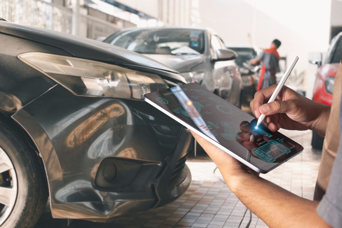 Repair advisor documenting vehicle damage on a tablet in a collision repair facility