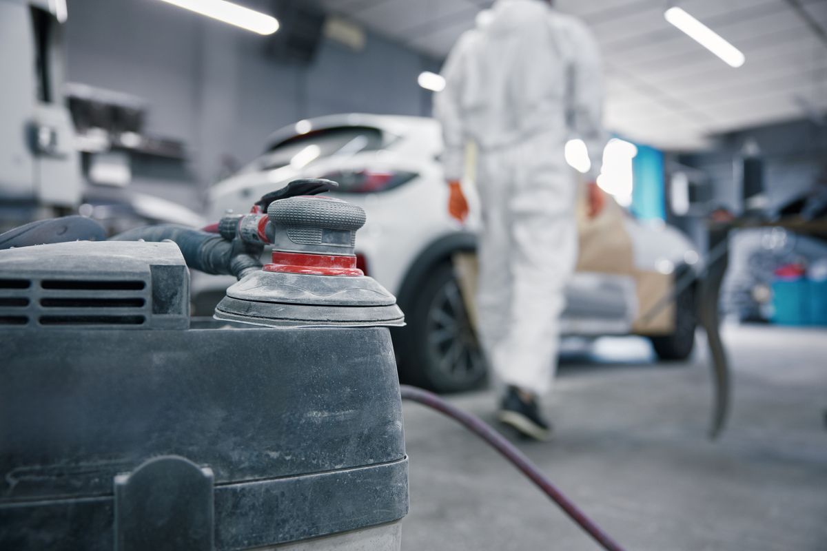 Refinish technician walking toward a vehicle prepared for the paint booth